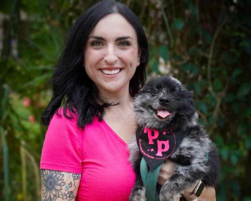 Lauren from Professional Pets Florida holding a dog in a branded bandana